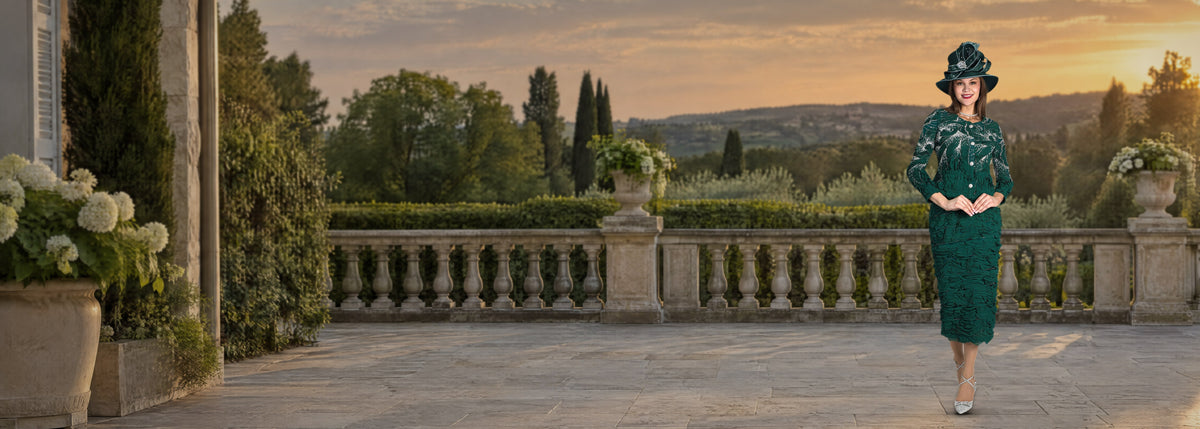 Lily and Taylor suit in emerald with a matching wide-brim hat, full length on a garden terrace at golden hour